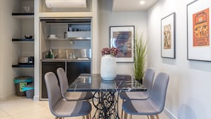 Una cocina moderna con horno empotrado, comedor con mesa de mármol y cuatro sillas, y aire acondicionado instalado en la pared.