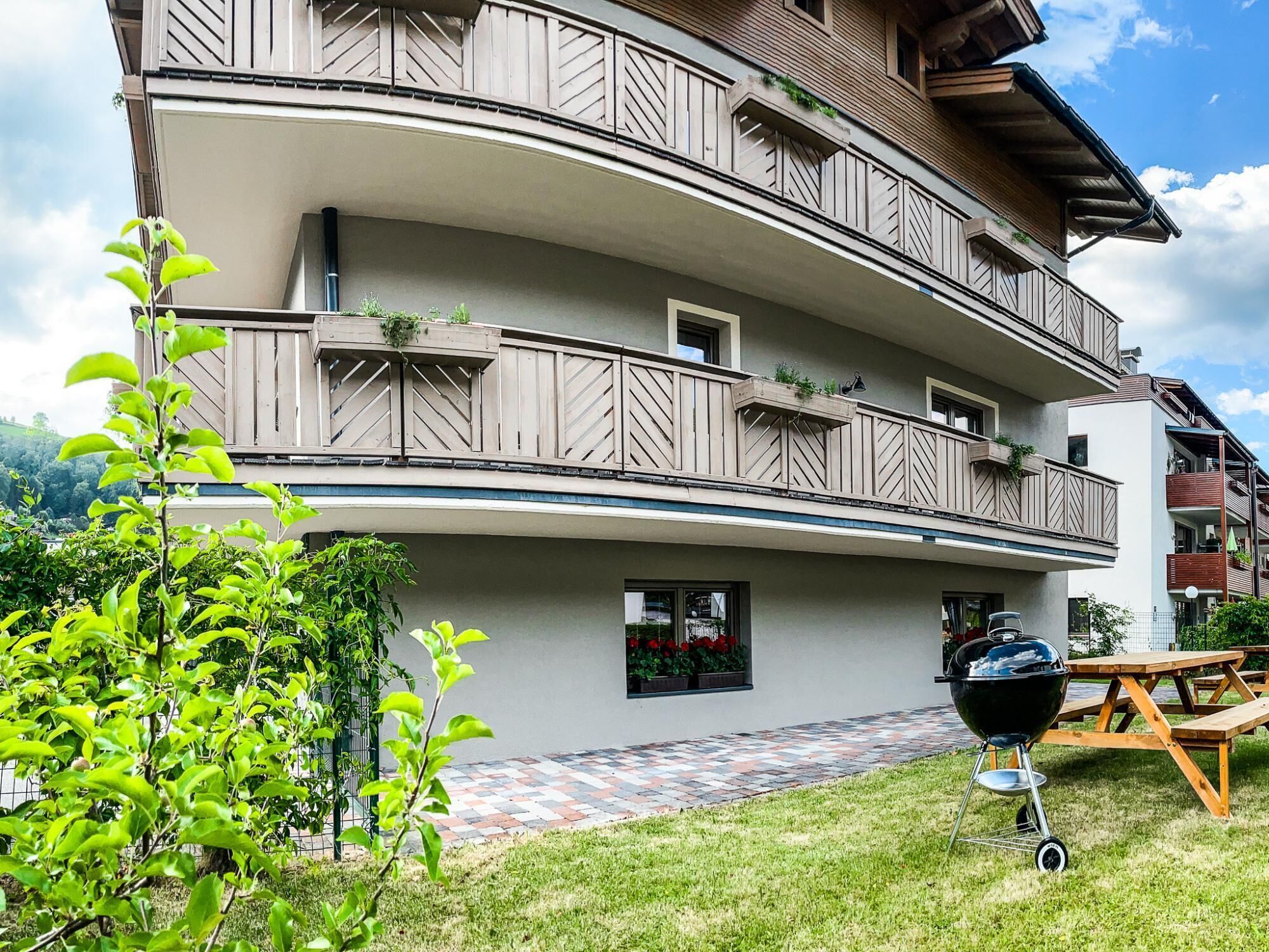 A multi-story building with balconies, a barbecue grill, and a checkered pathway.