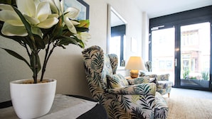 A living room with a potted plant, a patterned armchair, a sofa, and a lamp. - Living Eden - TOP 3 in Zell am See (Zell am See)