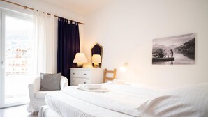 A hotel room with a bed, a chair, a desk with lamps, and a painting on the wall. - Living Eden - TOP 3 in Zell am See (Zell am See)