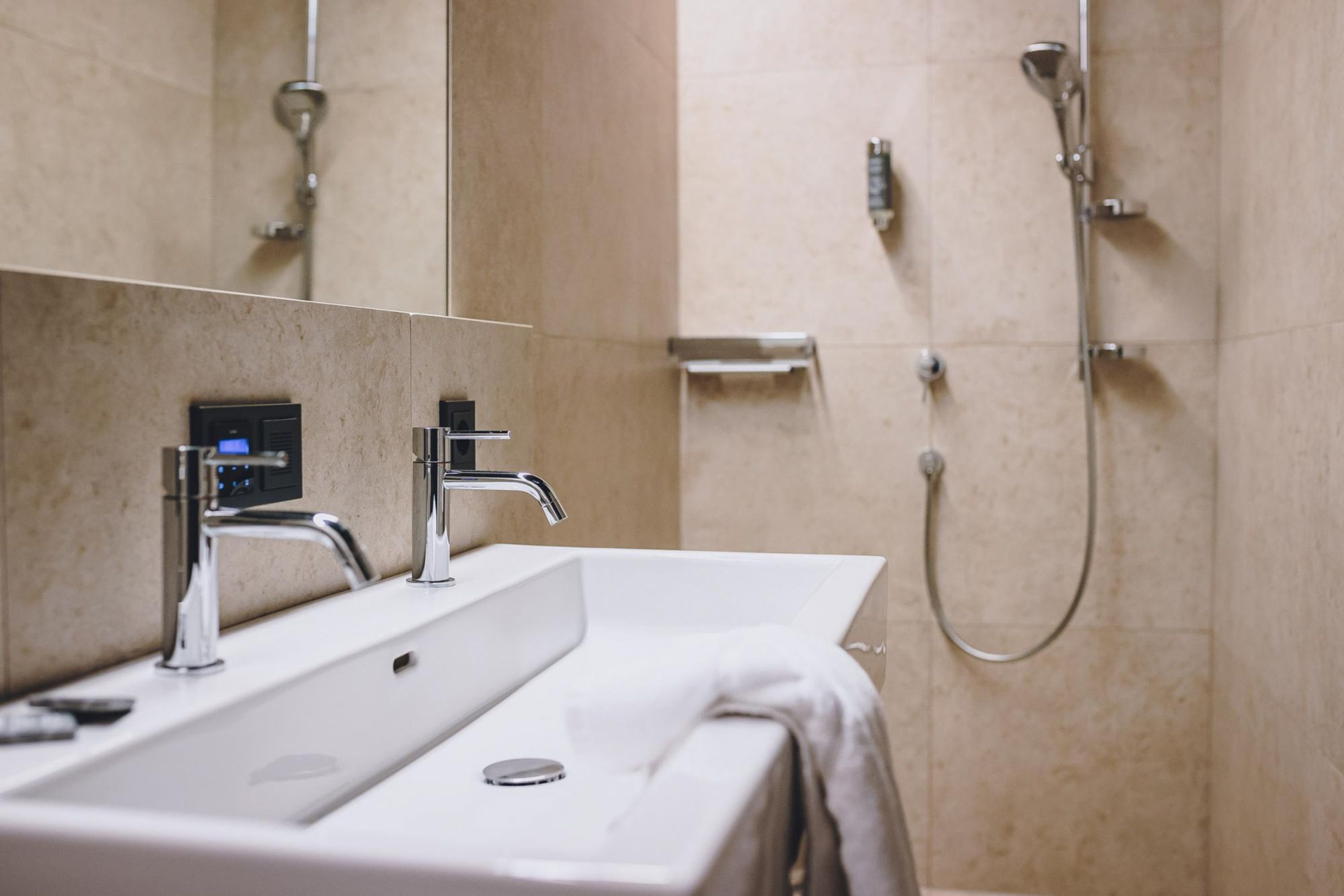 Un baño moderno con un lavamanos grande, un espejo y una zona de ducha.
