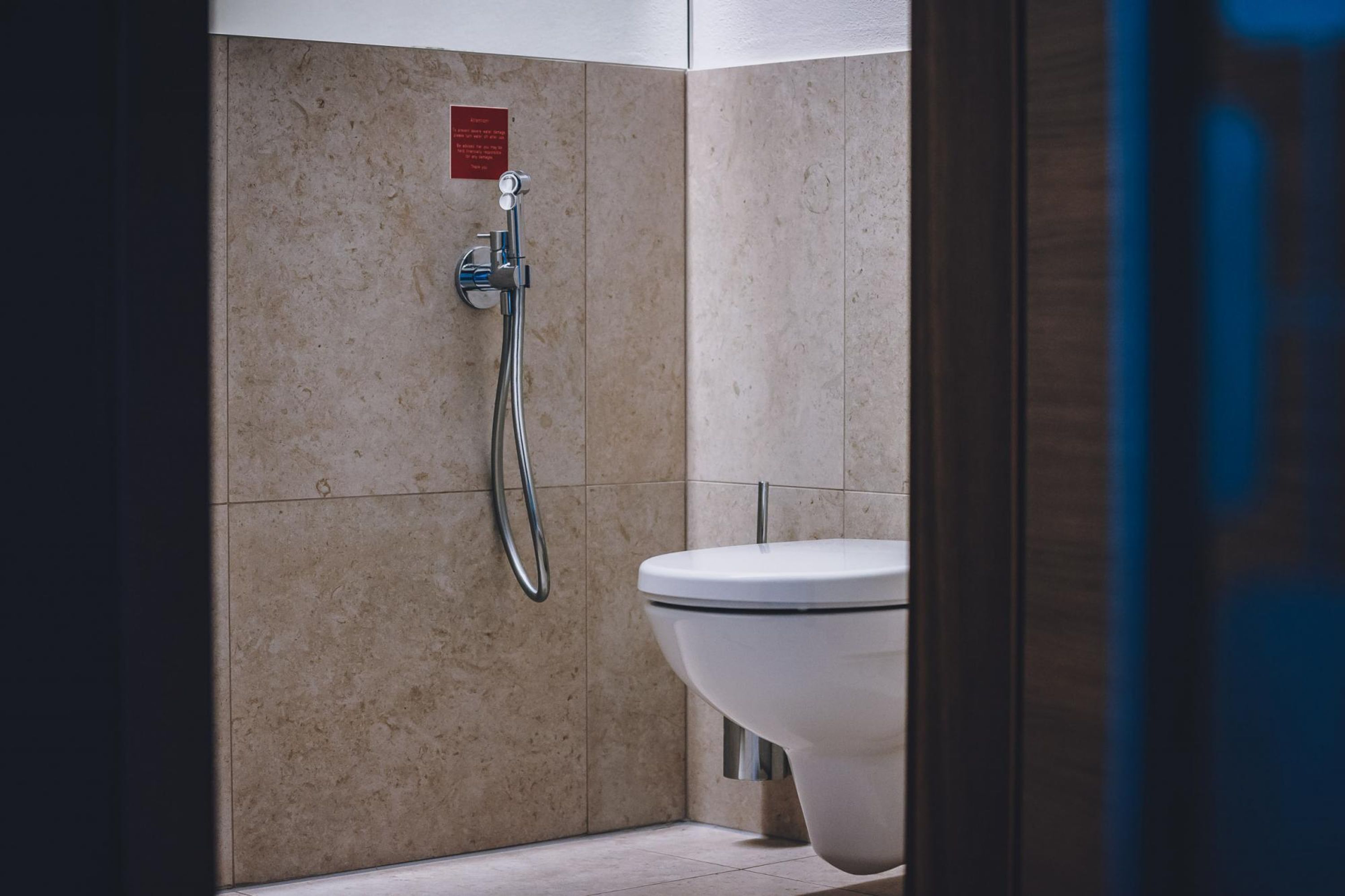 Un baño con ducha, inodoro y un cartel en la pared.