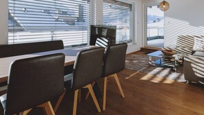 Una sala de estar moderna con una mesa de comedor de madera, sillas negras, un sofá y un taburete pequeño.