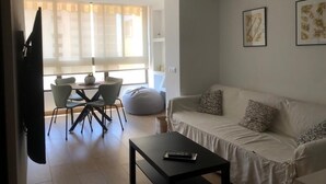Een woonkamer met een bank, een salontafel, en een eethoek met stoelen en een tafel.