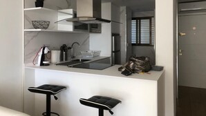 Een moderne keuken met een centraal eiland, barkrukken, een magnetron en een ingebouwde oven.