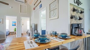 A dining area with a wooden table set for four, blue glassware, and a coffee station with pots and a coffee maker. - Walk to Lake Erie — Renovated 2BR Huron Home Near Cedar Point & Kalahari (Huron)