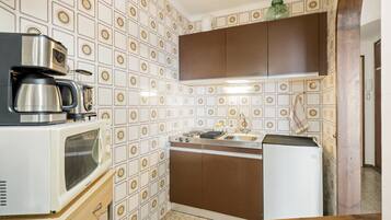 Una cocina compacta con cafetera, microondas y pileta.