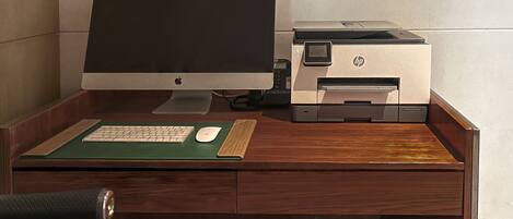 A wooden desk with a desktop computer, an HP printer, a keyboard, a mouse, and a green mouse pad.