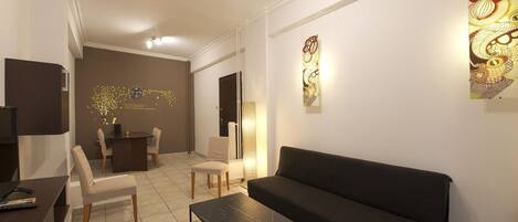 A modern living room with a black sofa, a coffee table, and a dining area with chairs and a table.