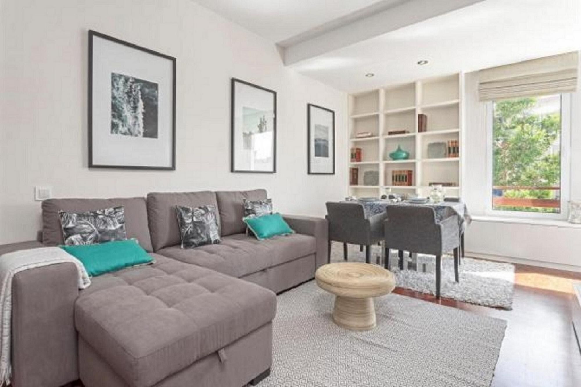 A modern living room with a grey sofa set, a round wooden coffee table, and a dining area with a white table and chairs.