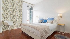 Camera da letto con un letto, comodini, una sedia e una parete decorata.