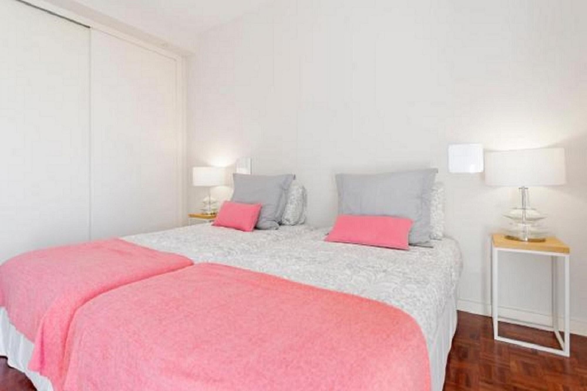 A bedroom with a bed, pillows, a bedside table, and a nightstand.