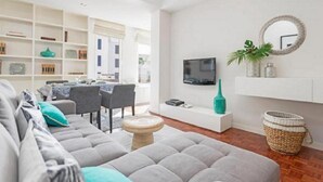 Un soggiorno moderno con un divano grigio, un tavolino rotondo e una TV fissata al muro.