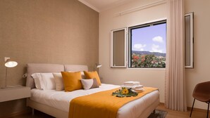 Hotellihuone, jossa on sänky, yöpöytälamput, ikkunasta avautuva näkymä ja tuoli.