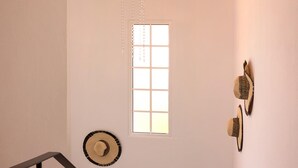 A staircase with a wrought iron railing, a decorative light fixture, and wall-mounted hats. - Sea View Villa by Homie (Santa Cruz)