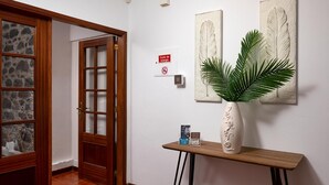 A hallway with a wooden door, a stone-framed window, and a wall-mounted sign. - Sea View Villa by Homie (Santa Cruz)