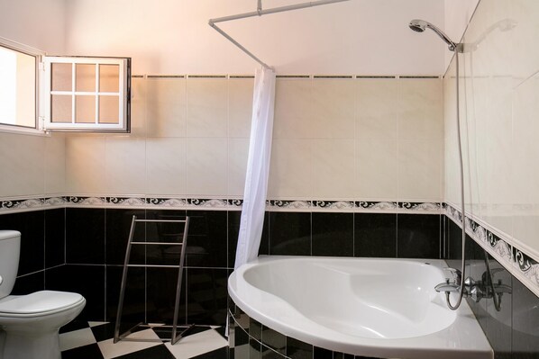 Un baño con una bañera blanca, un inodoro y una zona de ducha.
