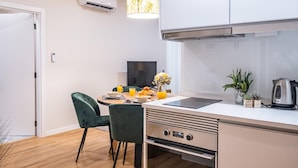 A modern kitchen with a dining area, featuring a built-in oven, a coffee maker, and a dining table with chairs. - Urban Paradise I by Homie (Funchal)
