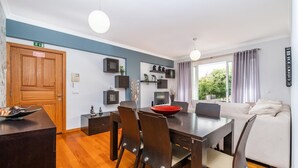 A modern dining area with a wooden table, chairs, and a red bowl centerpiece. - Home to Stay by Homie (Funchal)
