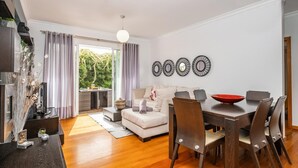 A modern living room with a dining area, a sofa, a coffee table, and a red bowl on the table. - Home to Stay by Homie (Funchal)