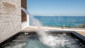 A hot tub with a waterfall feature, a wooden deck, and a view of the ocean. - Luxury Villa Cavo Mare Meltemi With Private Pool Jacuzzi (Zakynthos)