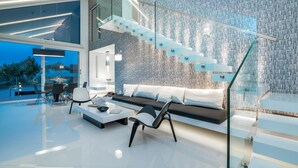 A modern interior with a glass staircase, a sofa, and a dining area. - Luxury Villa Cavo Mare Meltemi With Private Pool Jacuzzi (Zakynthos)