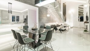 A modern kitchen with a glass dining table and chairs, a staircase with a unique design, and a living area with a sofa and coffee table. - Luxury Villa Cavo Mare Meltemi With Private Pool Jacuzzi (Zakynthos)