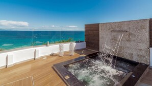 Eine Dachterrasse mit Whirlpool, Blick auf den Ozean und einer Holzverkleidung.