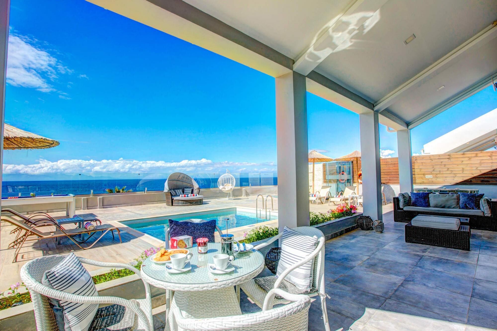 A rooftop terrace with a pool, outdoor seating, and a view of the ocean.