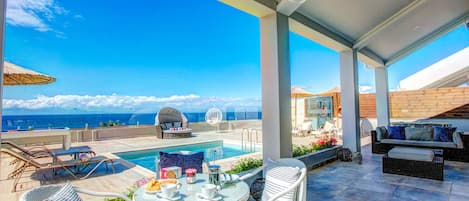 A rooftop terrace with a pool, outdoor seating, and a view of the ocean.