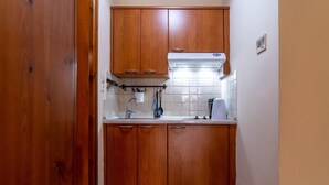 A compact kitchen with wooden cabinets, a white tiled backsplash, and a built-in stove. - Katrina Studio 2 Ground Floor (Rethymno)