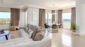 Uma sala de estar moderna com sofá, poltrona, mesa de jantar e cadeiras.