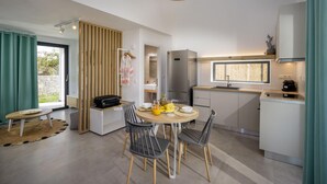 Una cucina moderna con zona pranzo, che include un tavolo rotondo, sedie, un frigorifero e una macchina per il caffè.