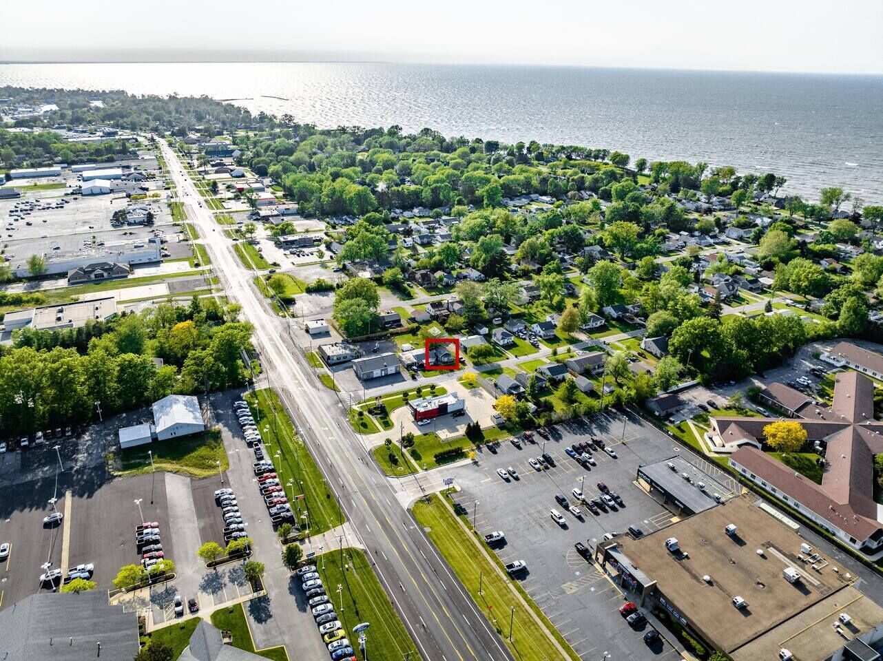An aerial view of a coastal town with a marina, residential areas, and a large parking lot.