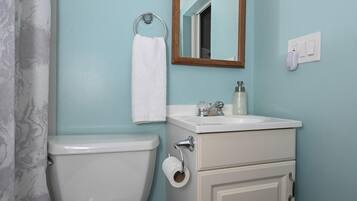 A bathroom with a toilet, sink, mirror, and towel rack.