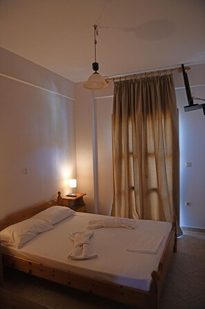Une chambre à coucher avec un lit en bois, une table de chevet avec une lampe, un luminaire suspendu et un rideau.