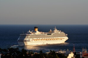 Ein großes Kreuzfahrtschiff mit mehreren Decks und einem markanten Schornstein, das auf offener See fährt.