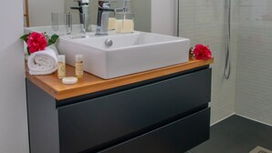 Een moderne badkamer met een witte wasbak, een spiegel en een douche.