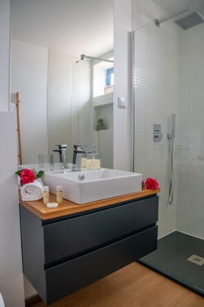 A modern bathroom with a white sink, a mirror, and a shower.