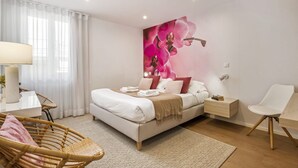 Een moderne slaapkamer met een bed, nachtkastjes, een stoel en een groot kunstwerk met bloemen op de muur.
