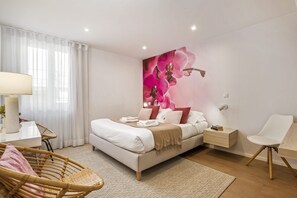 A modern bedroom with a bed, bedside tables, a chair, and a large floral wall art piece.