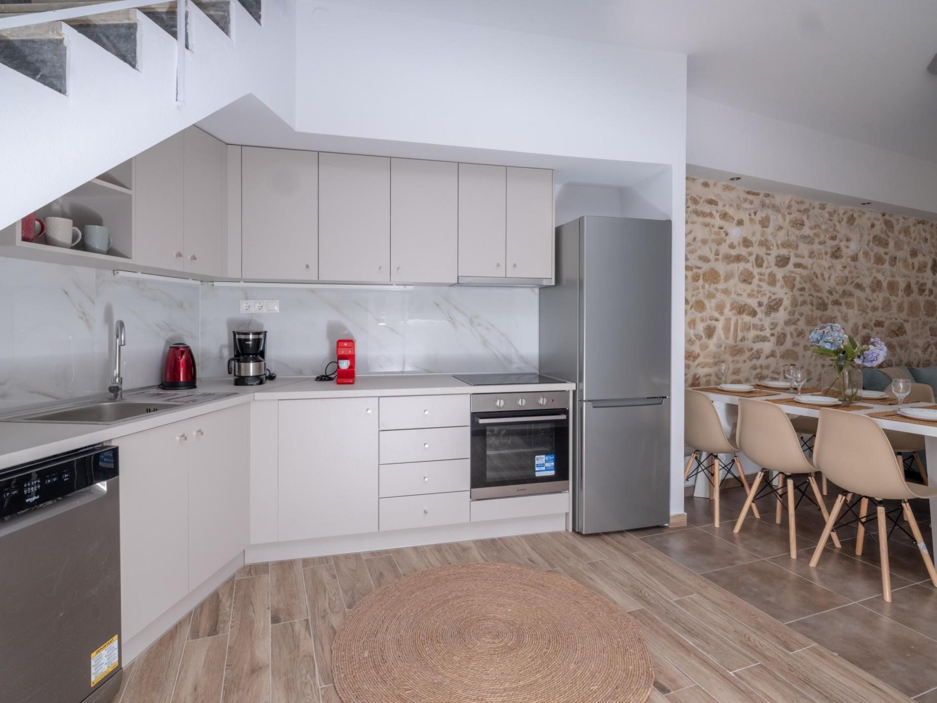 Una cocina moderna con armarios blancos, horno empotrado y refrigerador.