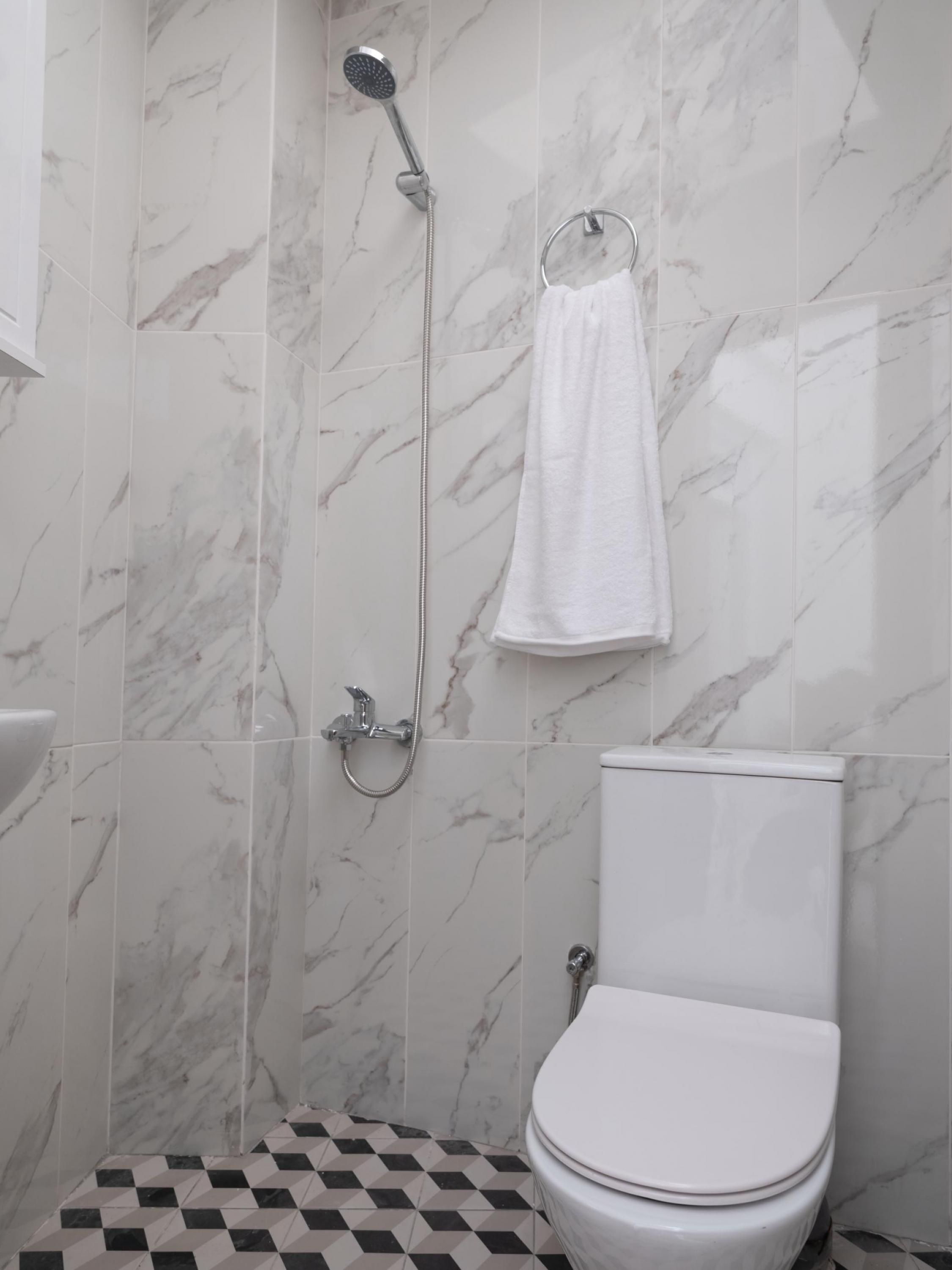 A bathroom with a toilet, a shower, and a towel rack.