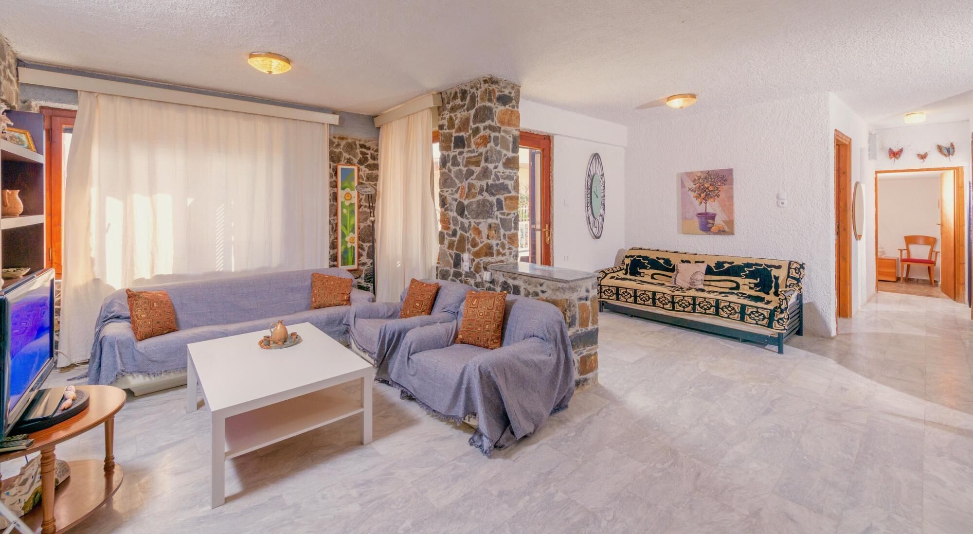 A living room with a stone wall, a sofa, a coffee table, and a TV.