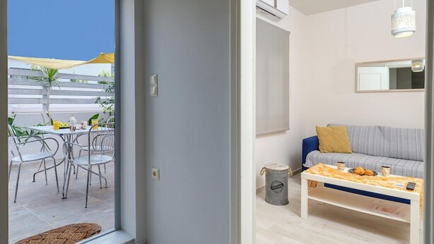 A modern living room with a sofa, coffee table, and a dining area with chairs and a table. - The Museum View Suite (Heraklion)