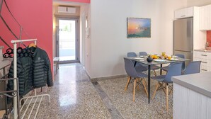 A modern kitchen with a dining area, a coat rack with jackets, and a painting on the wall. - The Museum View Suite (Heraklion)