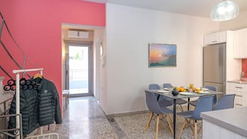 Uma cozinha moderna com área de refeições, um cabideiro com casacos e um quadro na parede.