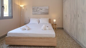 A bedroom with a bed, two bedside lamps, a painting on the wall, and a wardrobe. - The Museum View Suite (Heraklion)