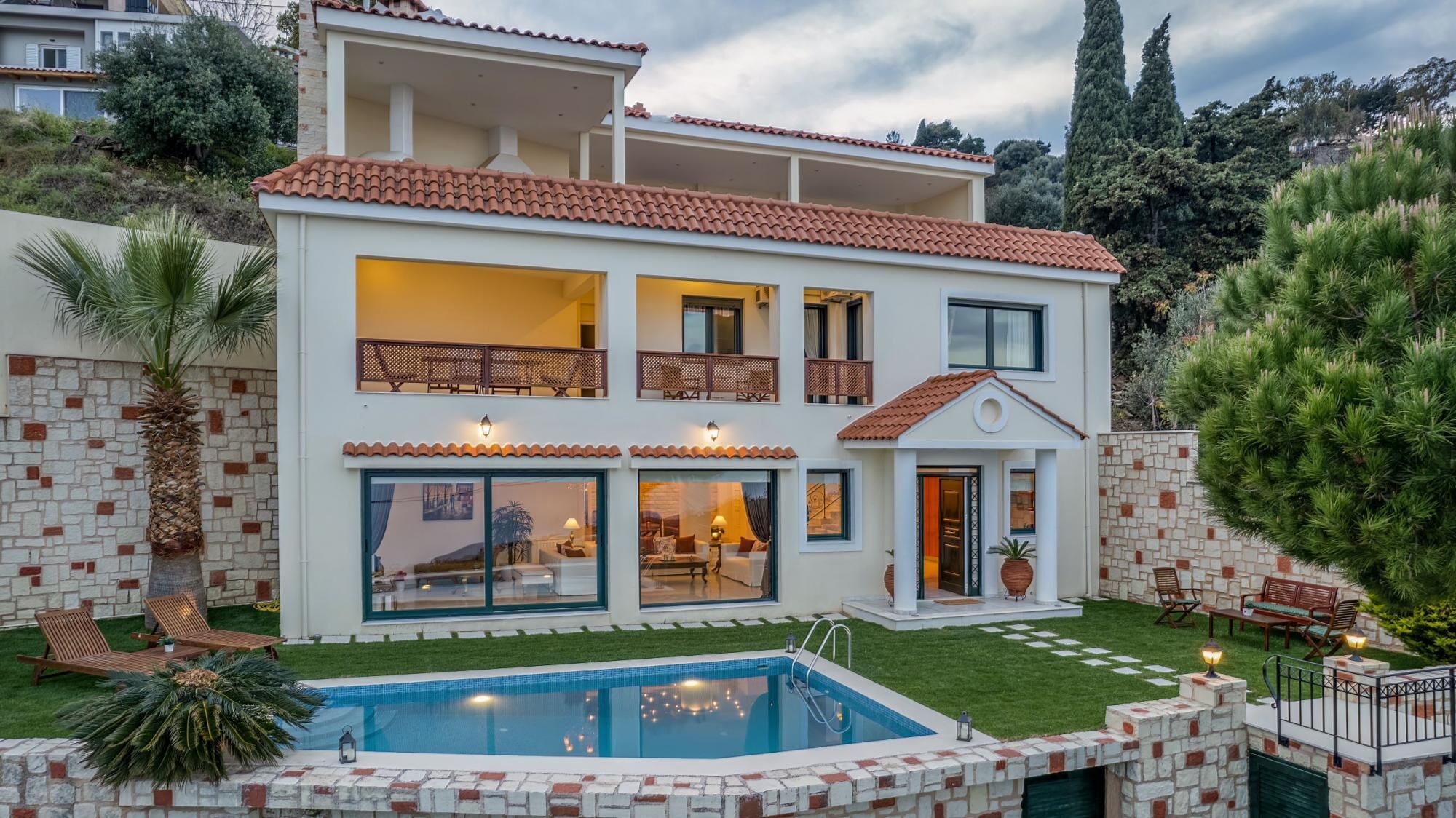 A two-story house with a swimming pool, balconies, and a well-maintained garden.
