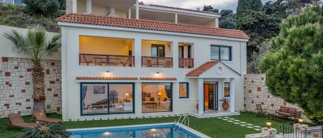 A two-story house with a swimming pool, balconies, and a well-maintained garden.